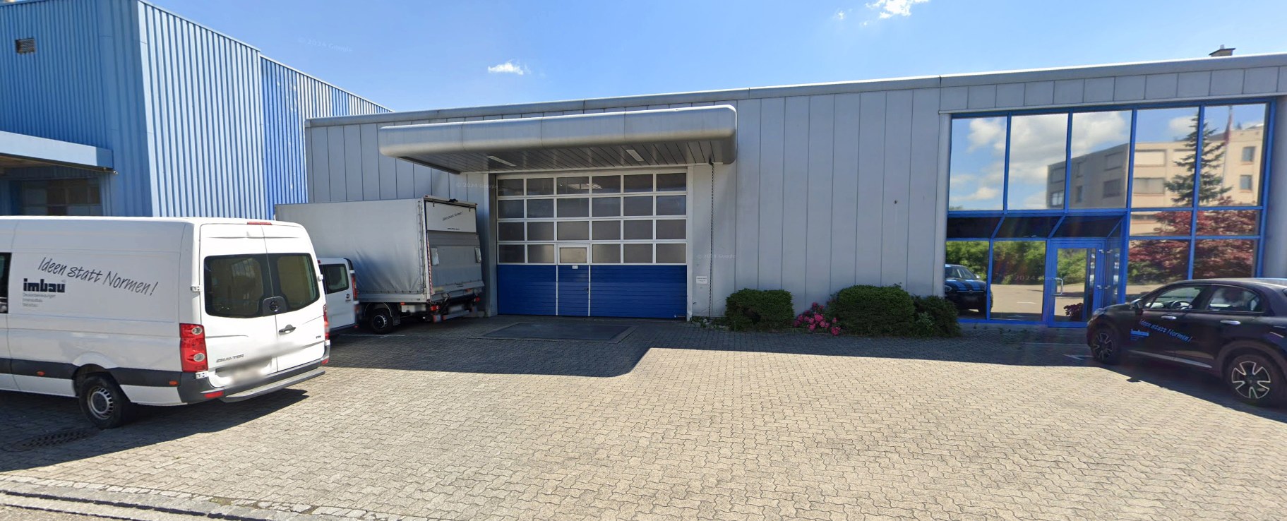 Firmengebäude der Imbau AG in Pratteln mit Firmenfahrzeugen vor der Werkhalle